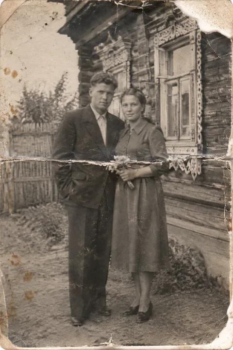 Исходник: выцветшее фото 1950-х, пара у деревенского дома, трещины и заломы